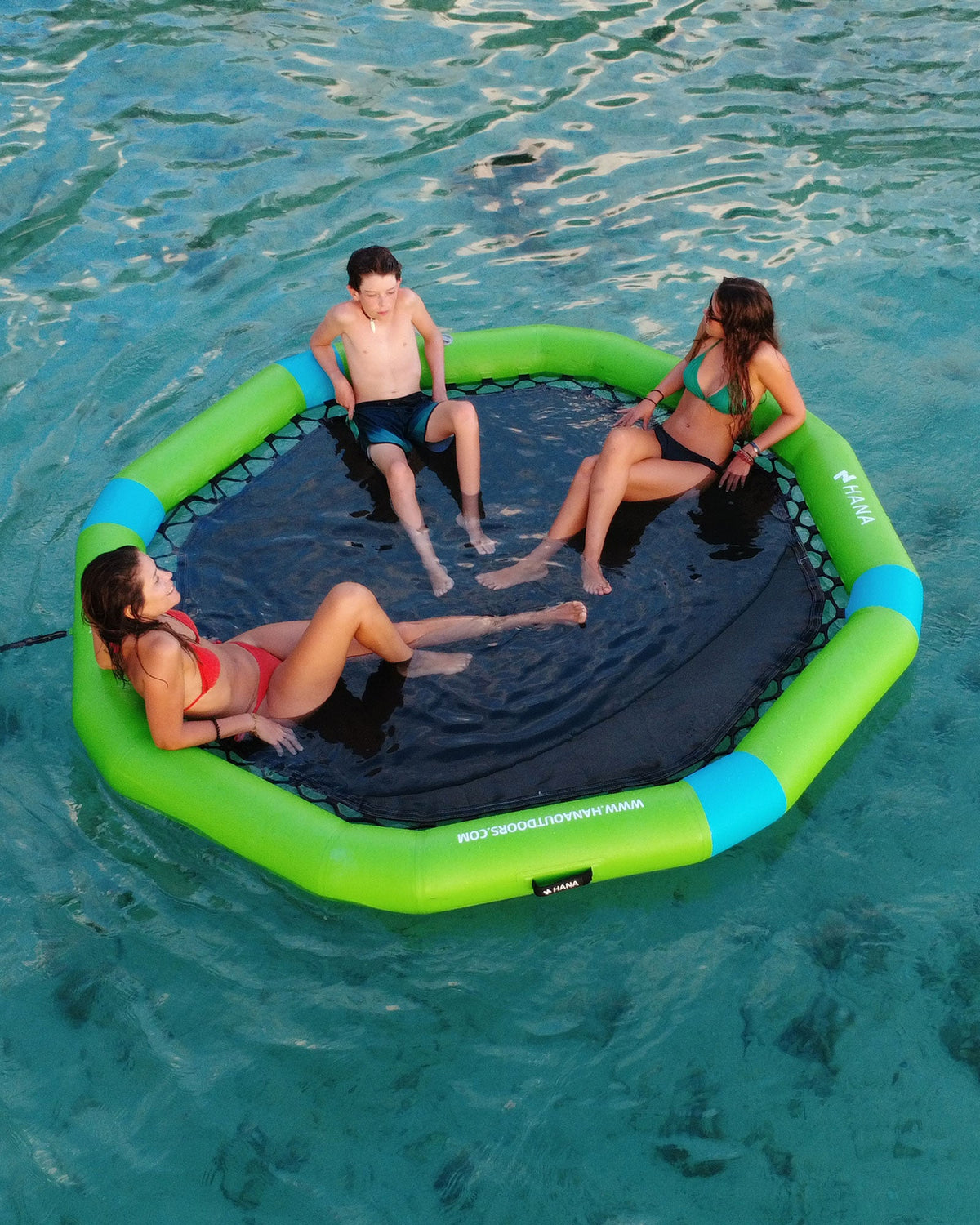 Three people relaxing on a green HANA floating platform