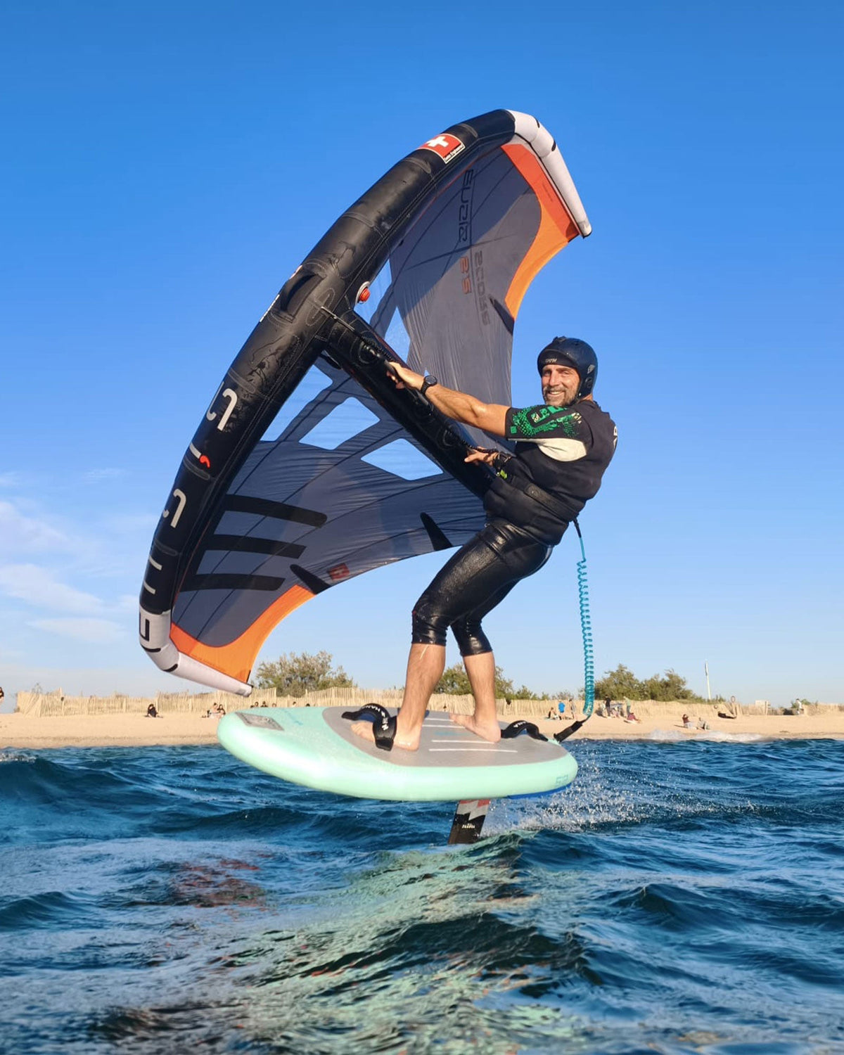 Rider en wingfoil volant au-dessus de l’eau près d’une plage