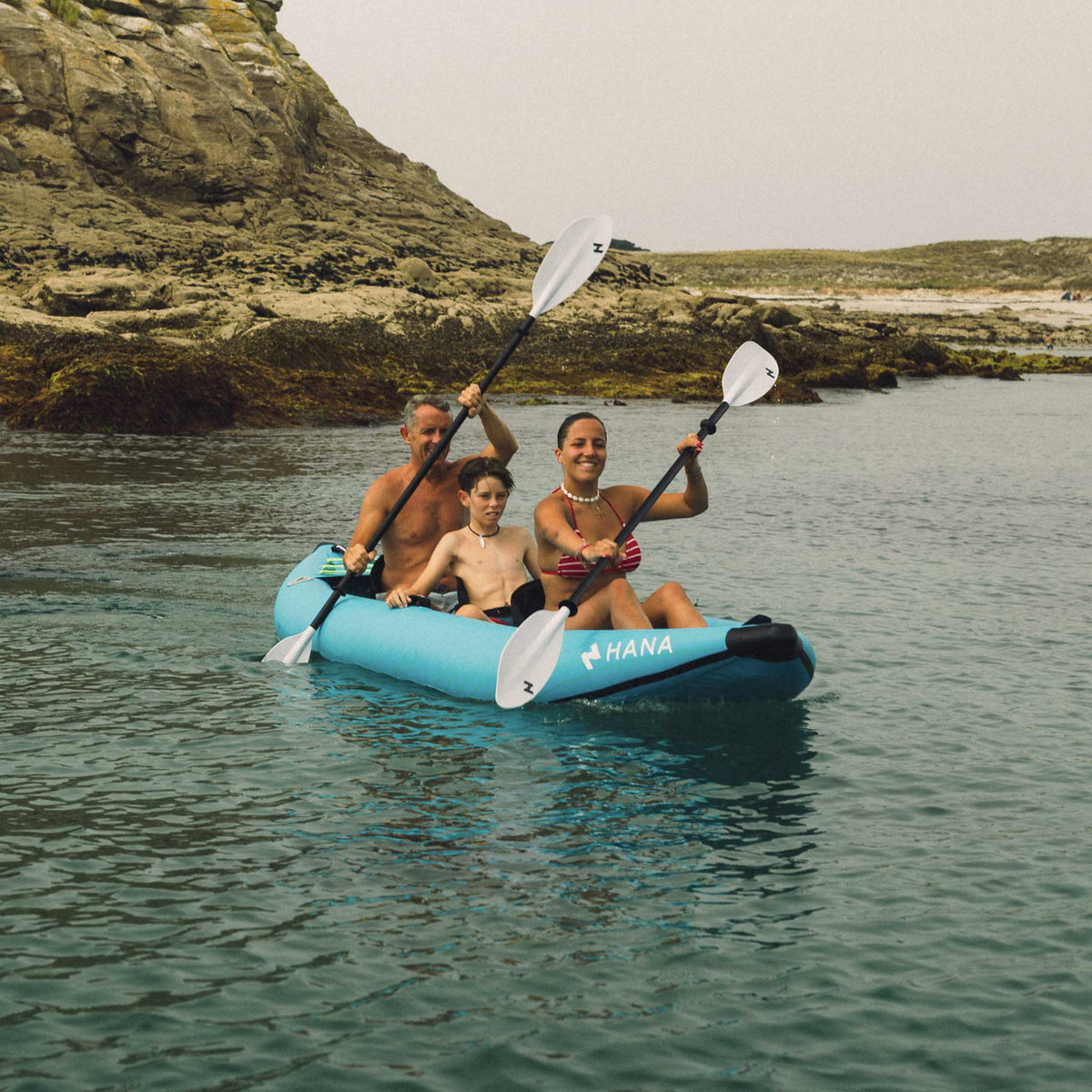 Kayak gonflable HANA Cruiser 2/3P bleu – pagayeurs en mer près d’une côte rocheuse