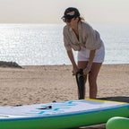 Woman inflating a paddle board with the HANA Premium double action pump on the beach