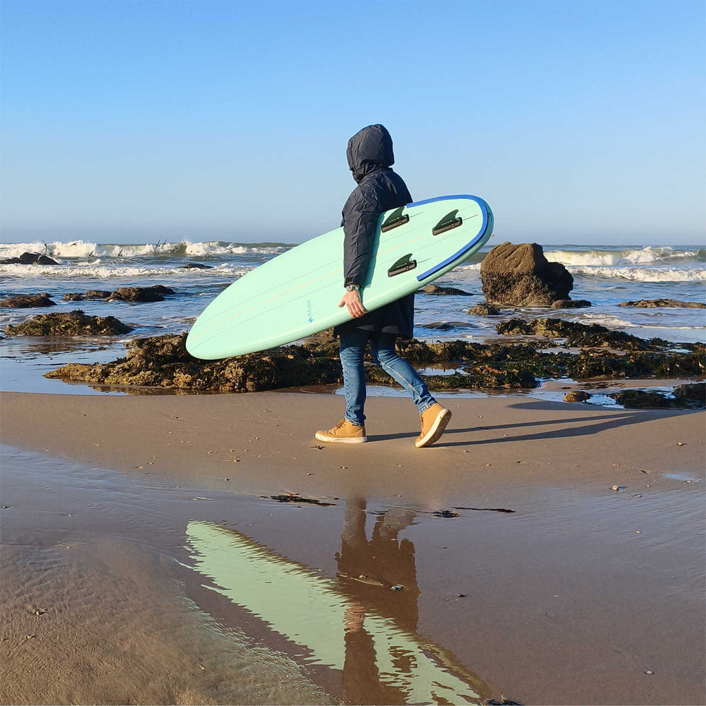 Surfeur marchant sur la plage avec la planche de surf gonflable HANA Premium 6'6