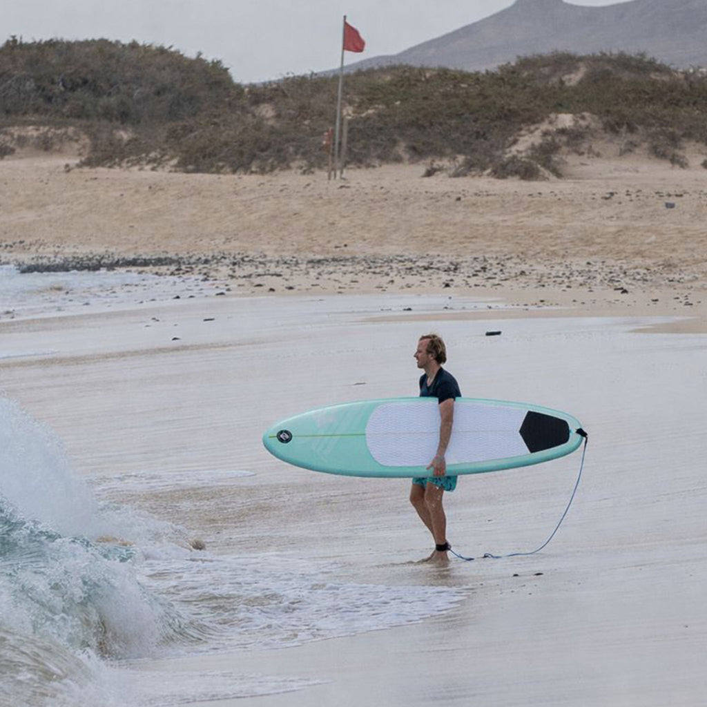 Surfer heading into the water with the HANA Premium 7'8 inflatable surfboard