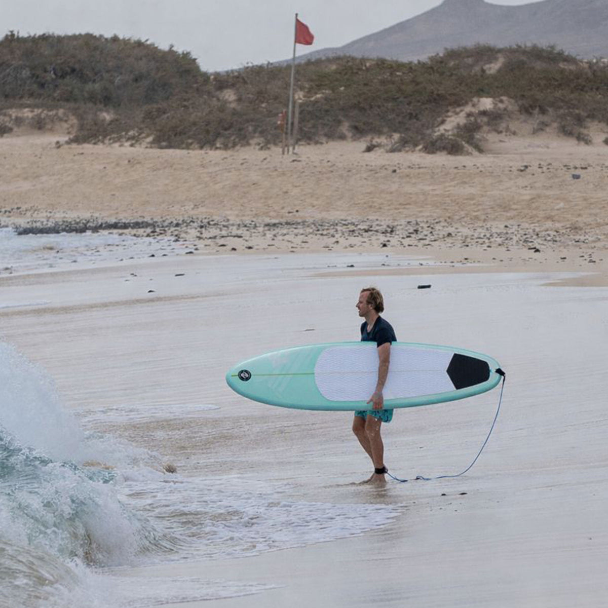 Surfer heading into the water with the HANA Premium 7'8 inflatable surfboard