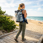 Woman wearing the HANA XPlorer 25L backpack in Graphite Blue on the beach