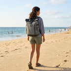 Woman wearing the HANA XPlorer 25L backpack in Dark Grey on the beach